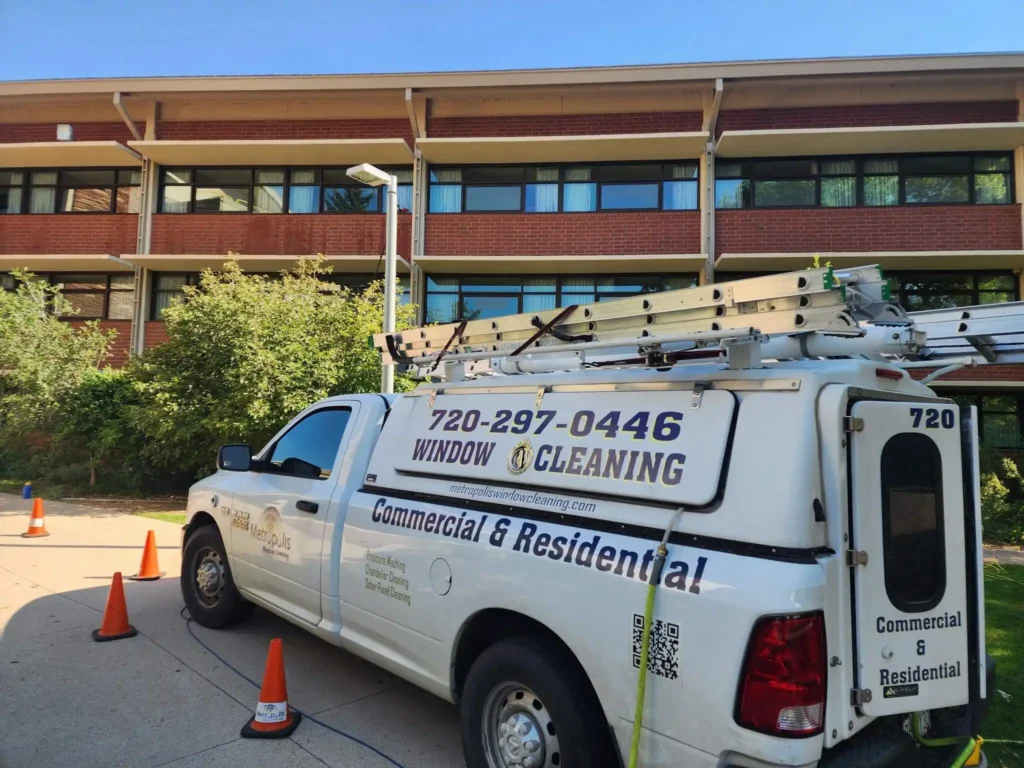 Branded Metropolis Window Cleaning service truck equipped with ladders parked outside a commercial facility
